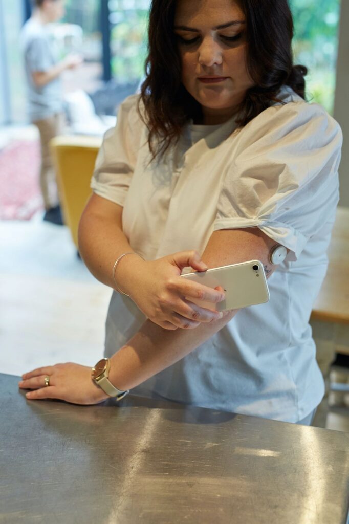 A woman is holding her phone while standing on the table.