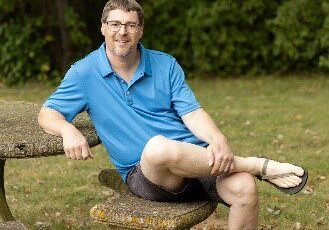 A man sitting on top of a stone bench.