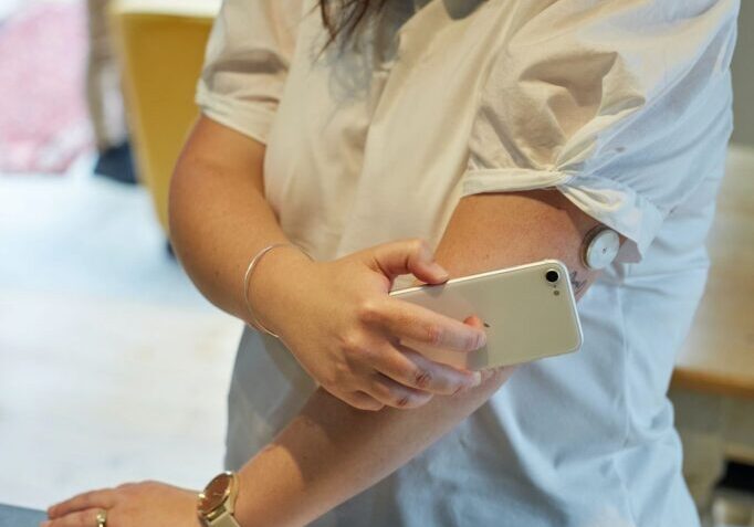 A woman is holding her phone while standing on the table.